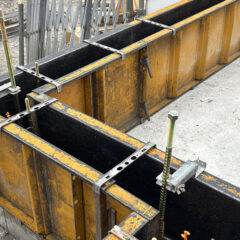 Close-up of yellow and black concrete formwork panels with metal clamps and braces set for pouring concrete