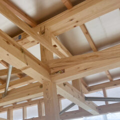 Wooden framing inside a partially built structure, showing intersecting wooden beams and metal connectors in an unfinished interior