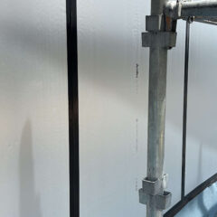Close-up of brushed metal siding panels attached to a scaffold at a construction site