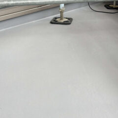 Gray, flat floor with metal scaffolding legs and base plates nearby on a construction site.