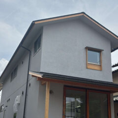 Two-story gray house with wood-trim window and a covered porch supported by wooden posts