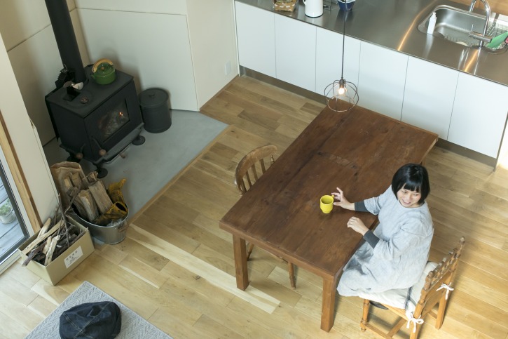 滋賀で注文住宅を建てる工務店のiKKAダイコーホームの薪ストーブで暖まる女性
